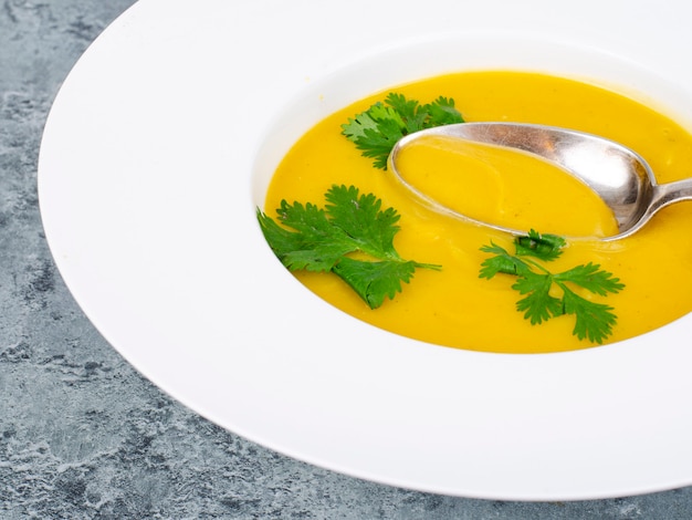 White plate with thick pumpkin cream soup. Studio Photo