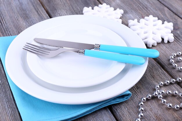 White plates, fork, knife and Christmas tree decoration on wooden background