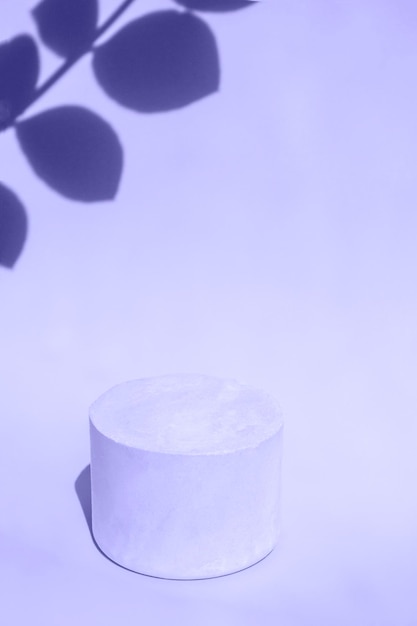 White podium close up on a very peri background with hard shadows of tropical plants Vertical Format