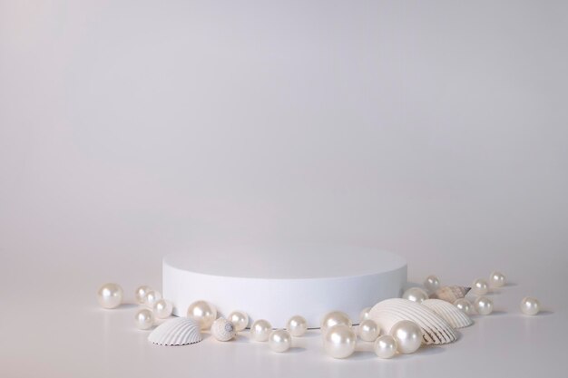 Photo white podium on the white background with pearls and seashells podium for product cosmetic