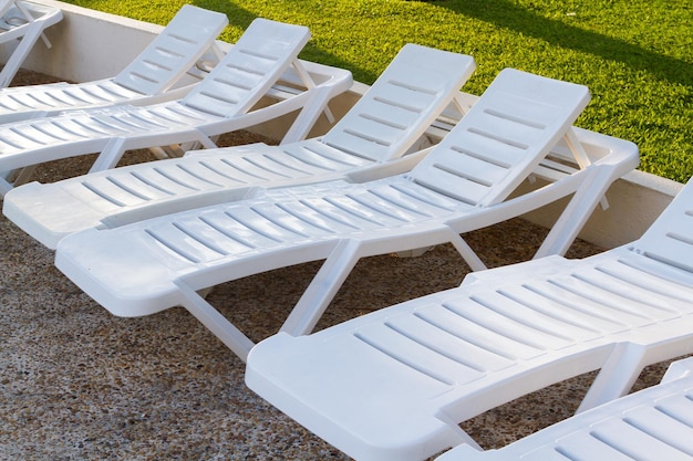 White pool chairs near the swimming pool at vacation resort in Mexico.