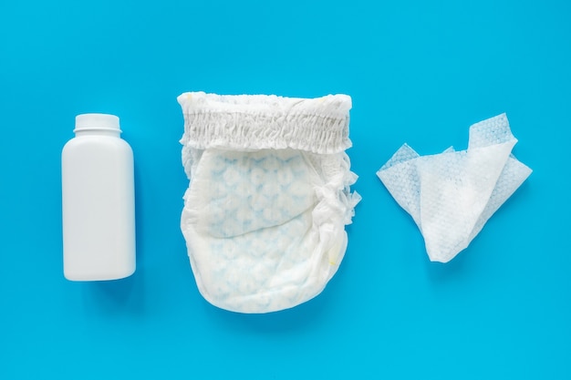 White powder, diaper, cream, napkin on a blue background, flatley, top view, copy space, mock up