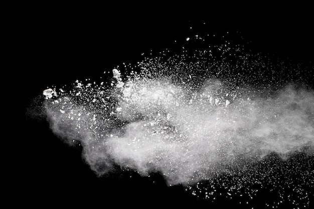 White powder explosion cloud against black background. White dust particles splash