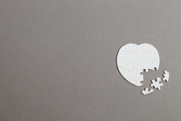 Photo white puzzle heart on grey wooden background