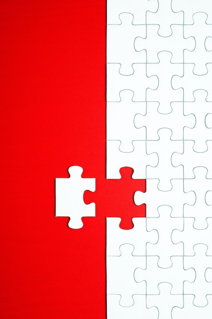 White puzzle pieces on a red background separated