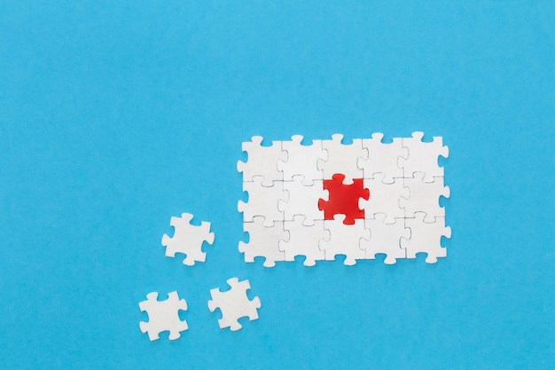 White puzzles and one red on a blue background flat lay