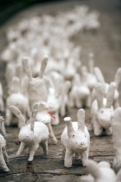 White rabbit statues made of plaster at outdoor art exhibition funny white hares on street