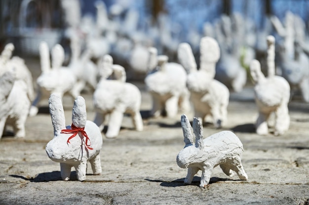 White rabbit statues made of plaster at outdoor art exhibition funny white hares on street