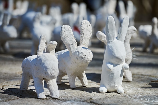 White rabbit statues made of plaster at outdoor art exhibition funny white hares on street