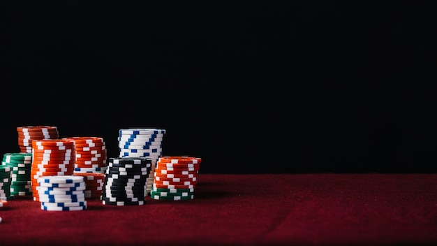 White; red; black and green casino chip stack on red poker table