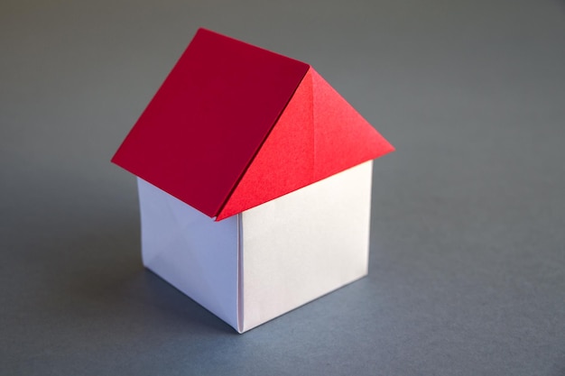 White and red paper house origami isolated on grey background