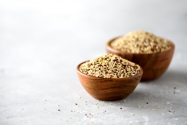 White and red raw organic quinoa in wooden bowl and rosemary. Healthy food ingredients. 