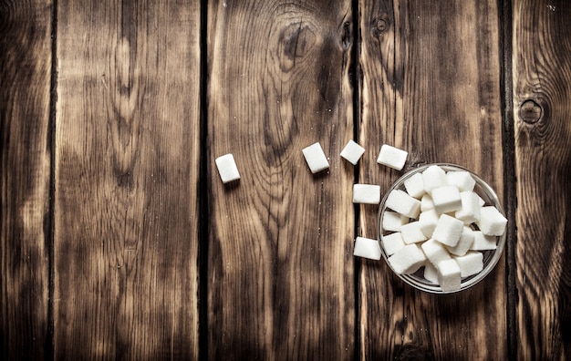 White refined sugar in the Cup. On wooden table.