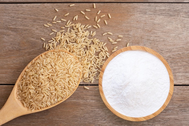 White rice flour in wooden bowl and brown rice isolated on wood table background Top view