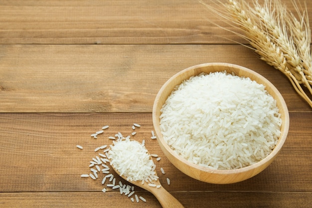 White rice (Thai Jasmine rice) in wooden bowl on wood background 