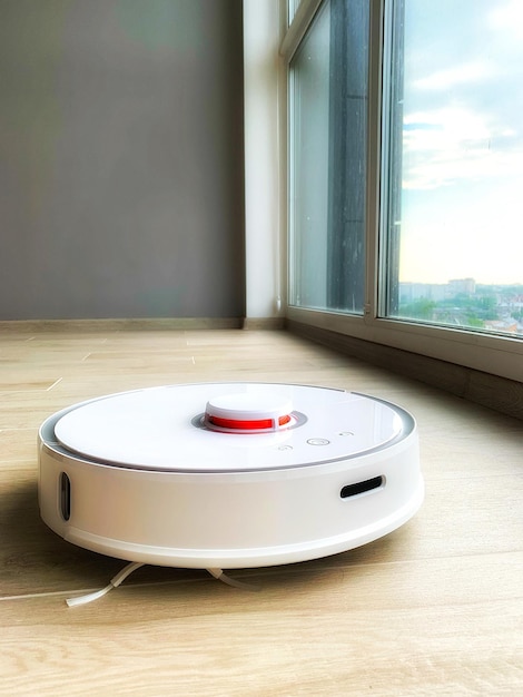 White robot cleaner robot vacuum cleaner on laminate floor in action