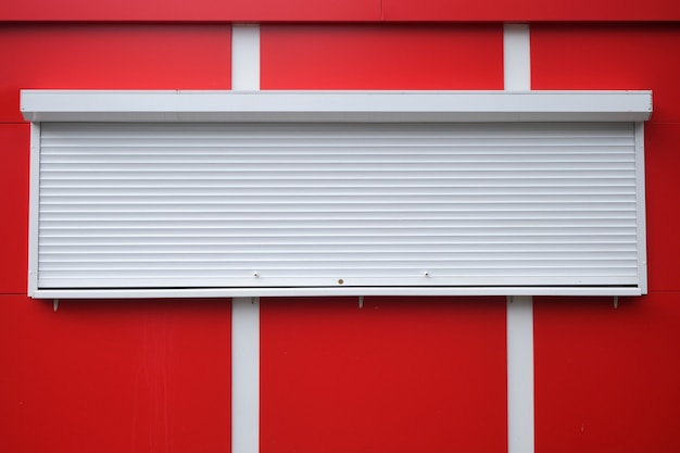 White roller shutters at a red kiosk. 