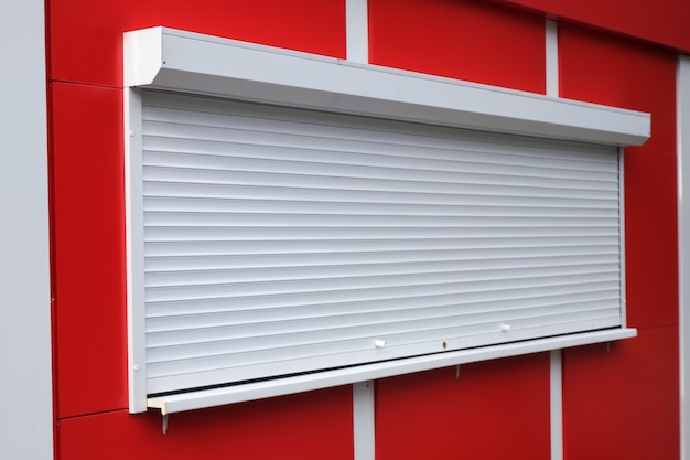 White roller shutters at a red kiosk. 