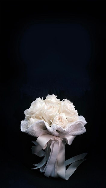 White rose bouquet with ribbon on dark background