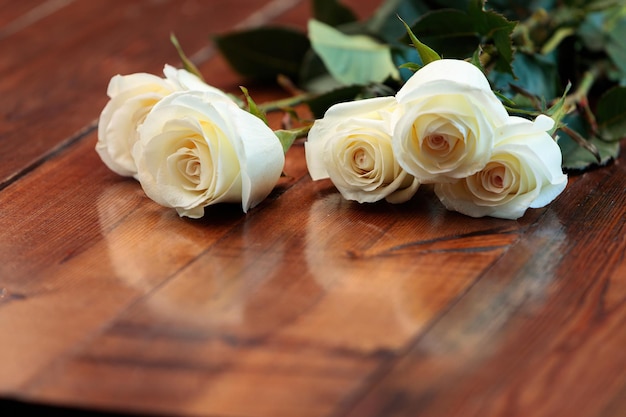 White roses lie on a wooden table.