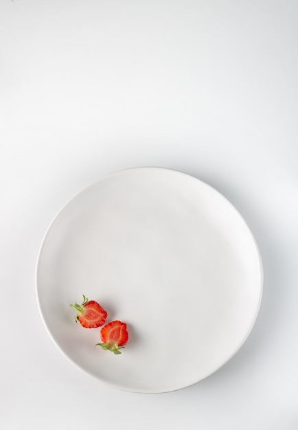 White round ceramic plate with strawberry pieces copy space