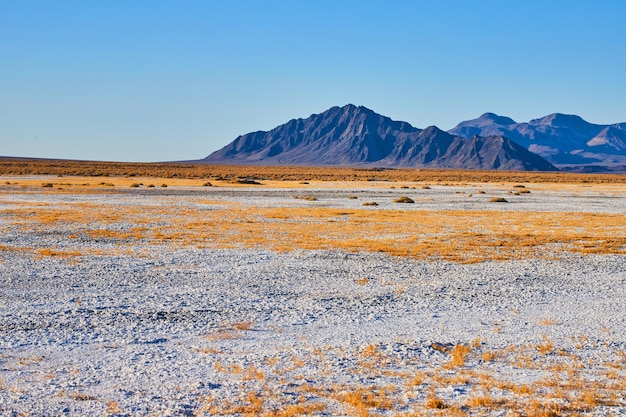 White sandy desert landscape leading to stunning black mountain