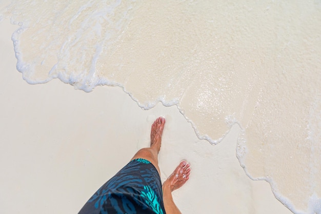 White sandy waves man barefoot on beach top view Summer vacation and holiday concept of travel