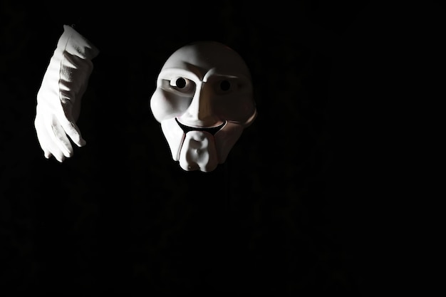 White scary mask on a black background with whites hand