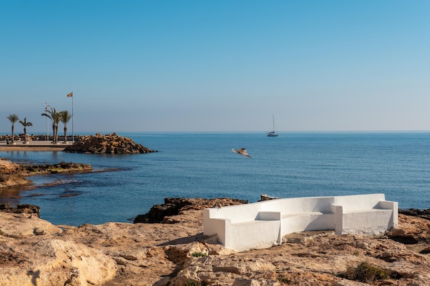 A white seat by the sea in the coastal town of Torrevieja next to Playa del Cura Alicante Valencian Community Spain Mediterranean Sea on the Costa Blanca