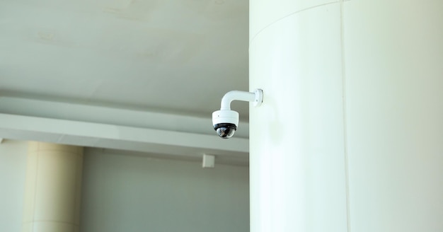 A white security camera on a white pole