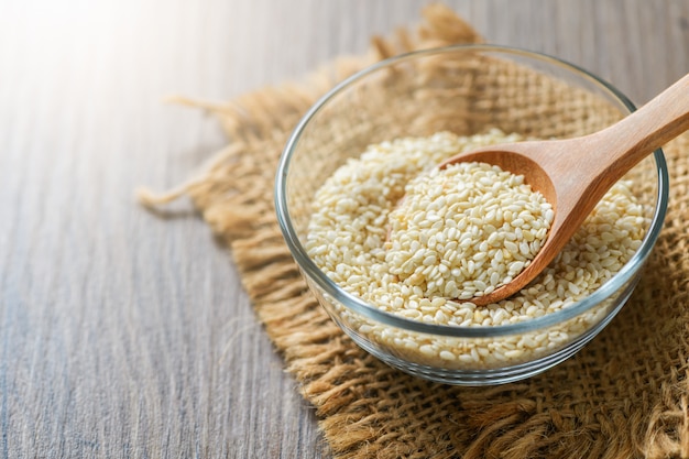 White sesame seeds in glass cup on wood table