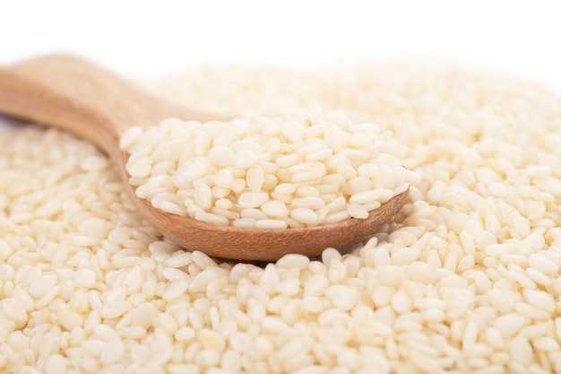 White sesame seeds organic in wooden spoon on white background. Health food concept.