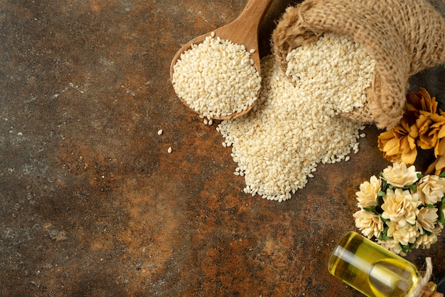 White sesame and sesame oil on wooden spoon. on rustic background top view 