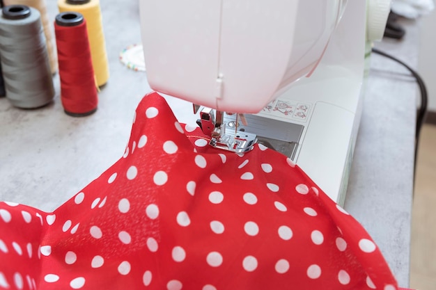 White sewing machine with red fabric in home tailor workshop