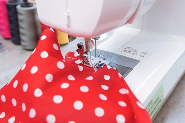 White sewing machine with red fabric in home tailor workshop