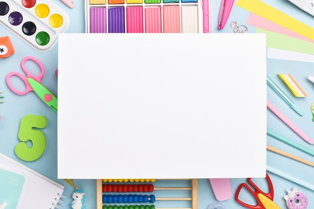 A white sheet of paper on the background of stationery. Back to school. Flat layout, top view, a place to copy.