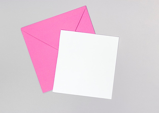 white sheet of paper on a pink envelope on a gray background