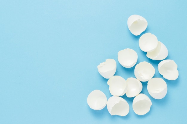 White Shell from broken eggs on a blue background. The concept of birth, cooking, replenishment in the family. Flat lay, top view.