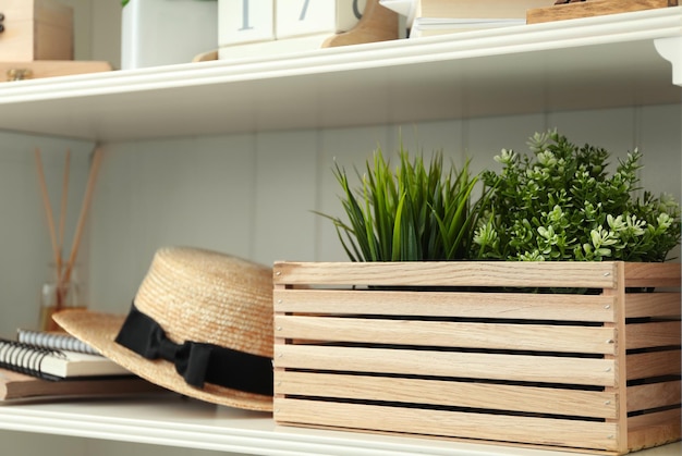 White shelving unit with plants and straw hat