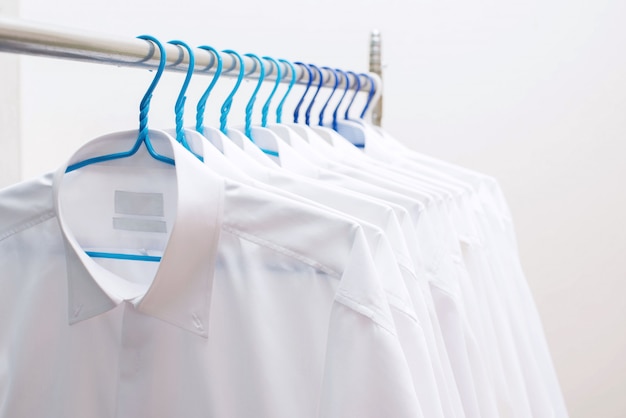 White shirts hanging on rack in a row