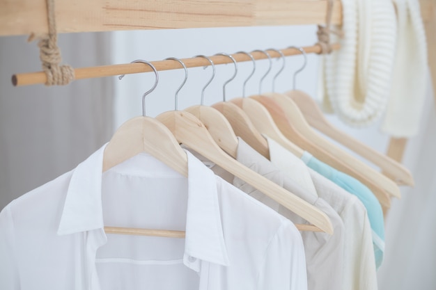 White shirts hanging on white built-in cloths racks