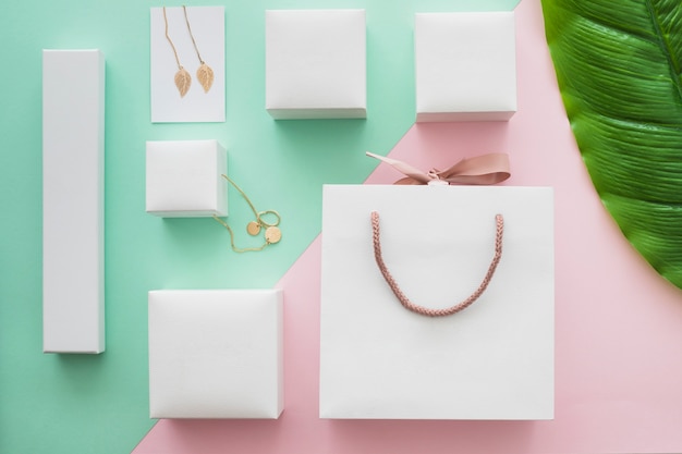 White shopping bag and jewel gift boxes on colored background