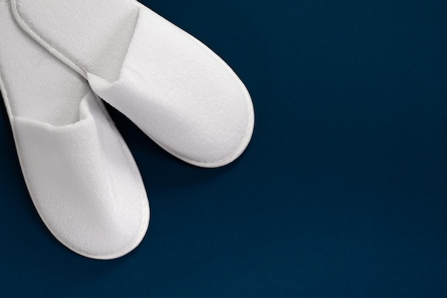 White slippers on a blue background with empty space Slippers for guests View from above