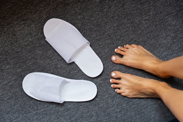 White slippers on rug and woman foots