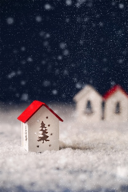 A white small house with a red roof on a blue background with snow a greeting card