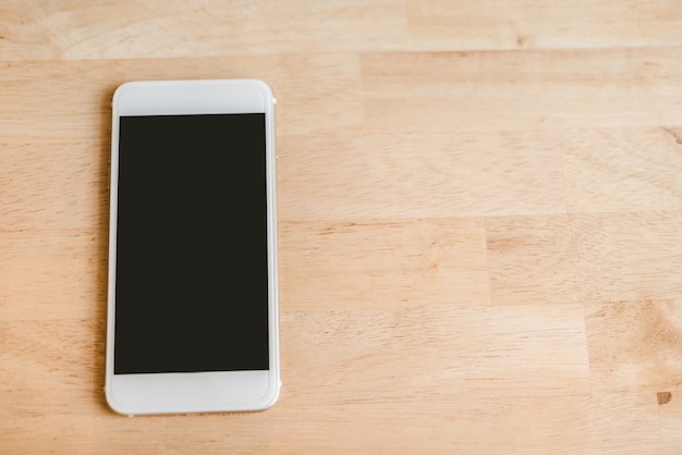 White smart phone with isolated screen on wooden desk. - Image