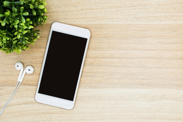 White smartphone with blank screen is on wood table. 