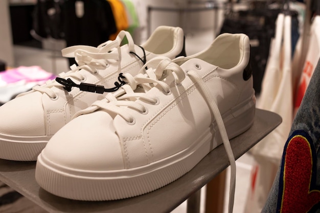 White sneakers on a shelf. Background of clothes racks out of focus. Fashion concept.