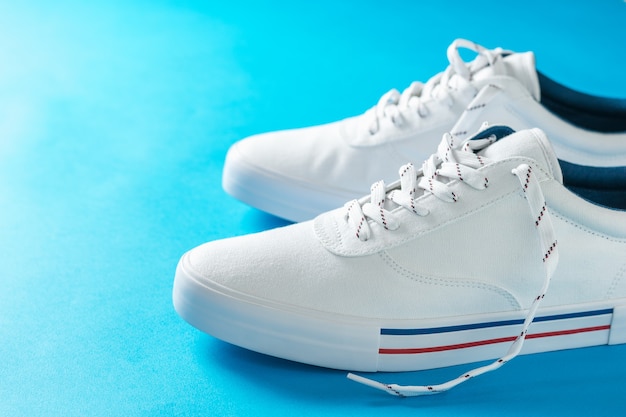 White sneakers with stripes on the sole on blue