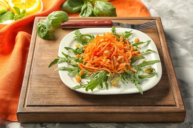 White square plate with delicious carrot raisin salad with green on wooden board